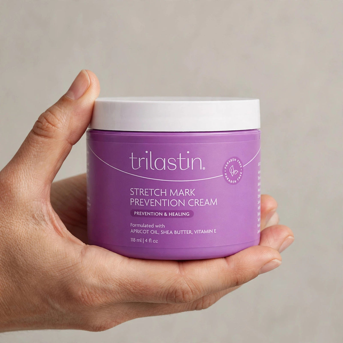 Hand holding the TriLASTIN stretch mark cream jar