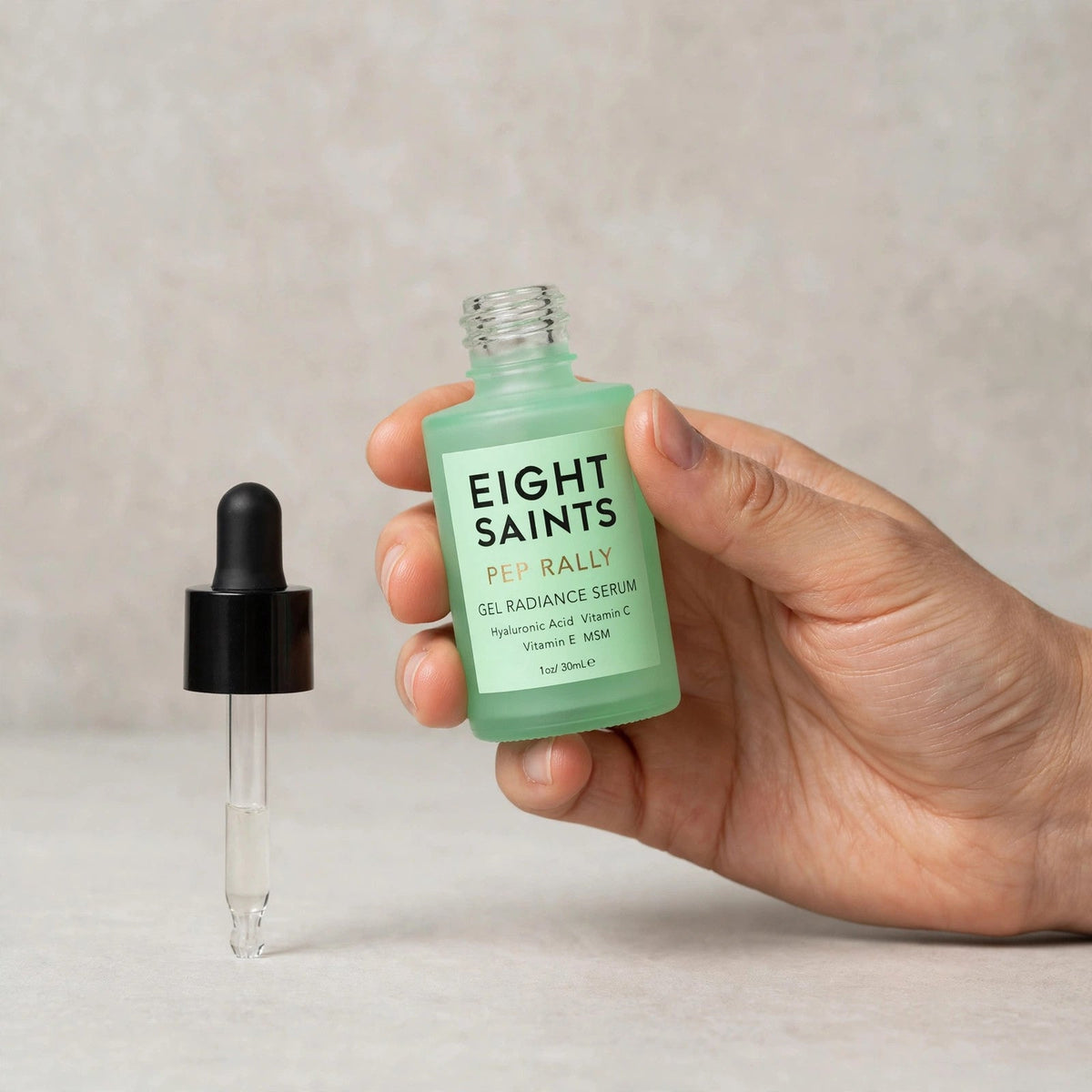 Hand holding the Eight Saints Pep Rally serum bottle