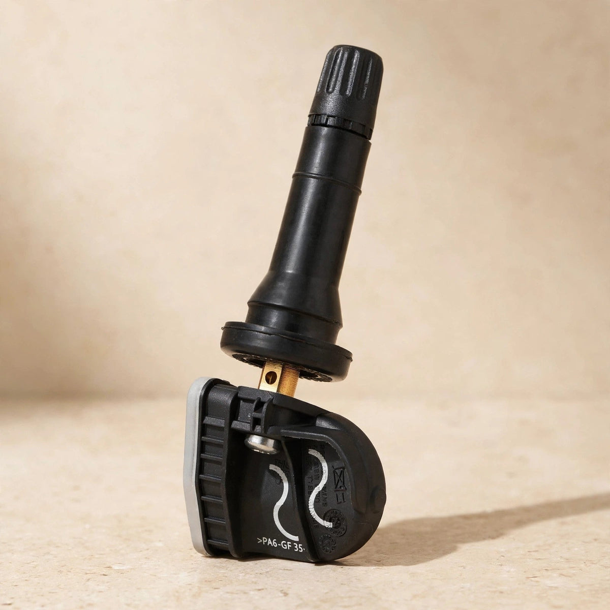 Ford HC3Z-1A189-A TPMS tire pressure sensor in a warm beige studio