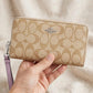 Coach zip-around long wallet in signature canvas held in hand