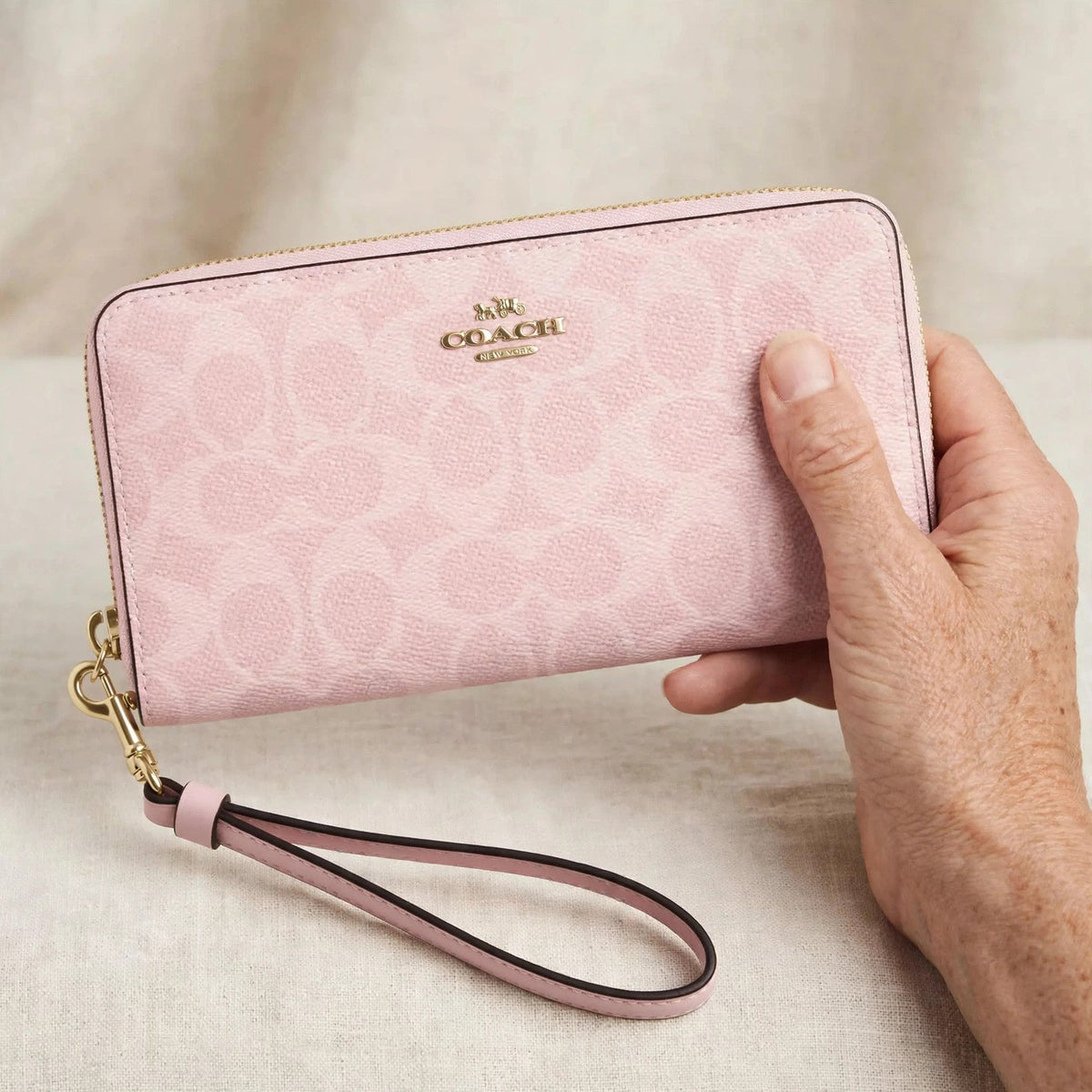Coach CW778 long zip-around wallet in powder pink held in hand