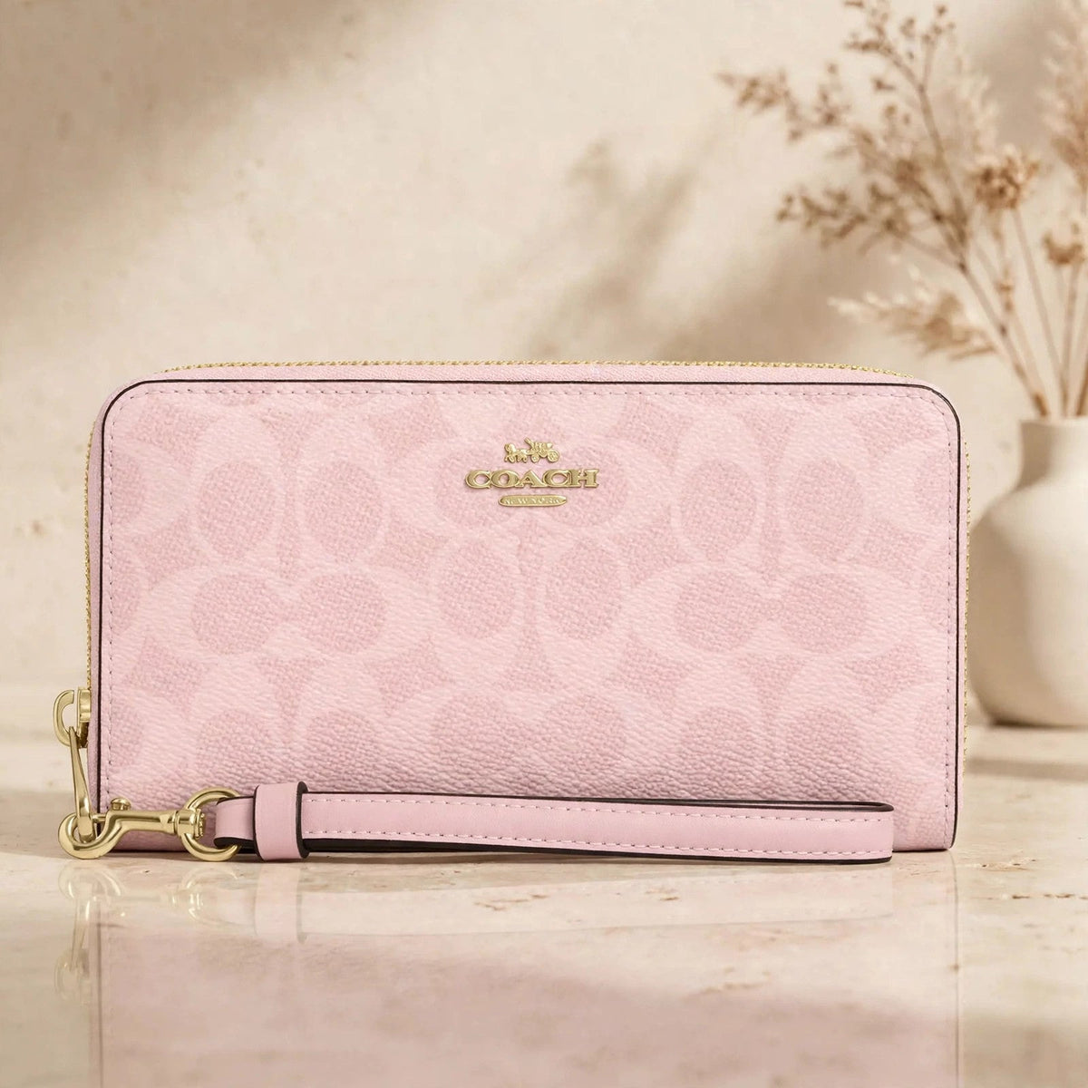 Coach CW778 long zip-around wallet in powder pink in a warm beige studio