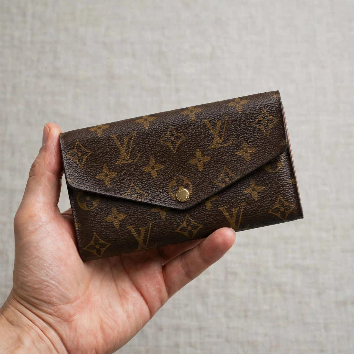 Louis Vuitton Portefeuille Sarah monogram long wallet held in hand
