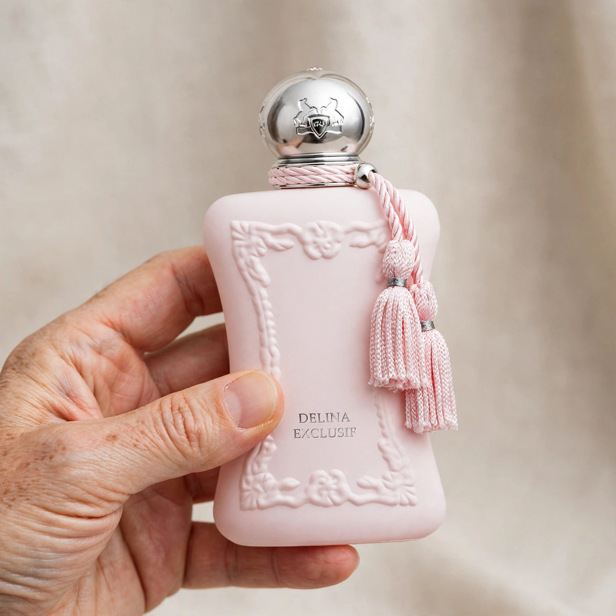Hand holding Parfums de Marly Delina Exclusif perfume bottle