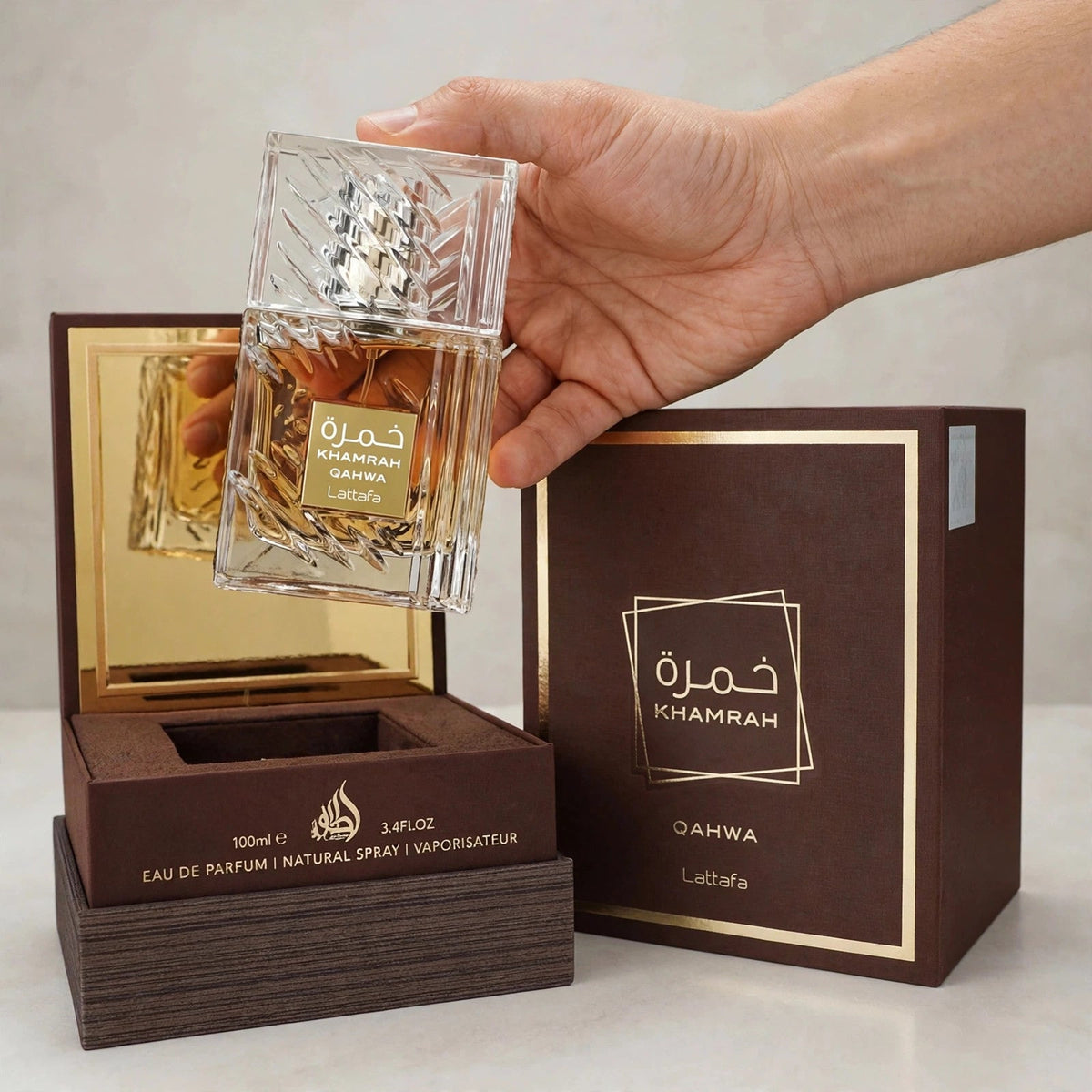 Lattafa Khamrah Qahwa Eau de Parfum bottle in hand setting