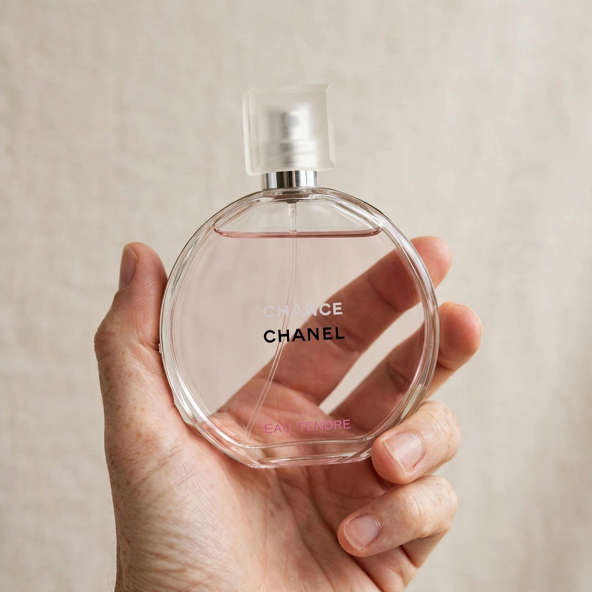 Hand holding Chanel Chance Eau Tendre perfume bottle