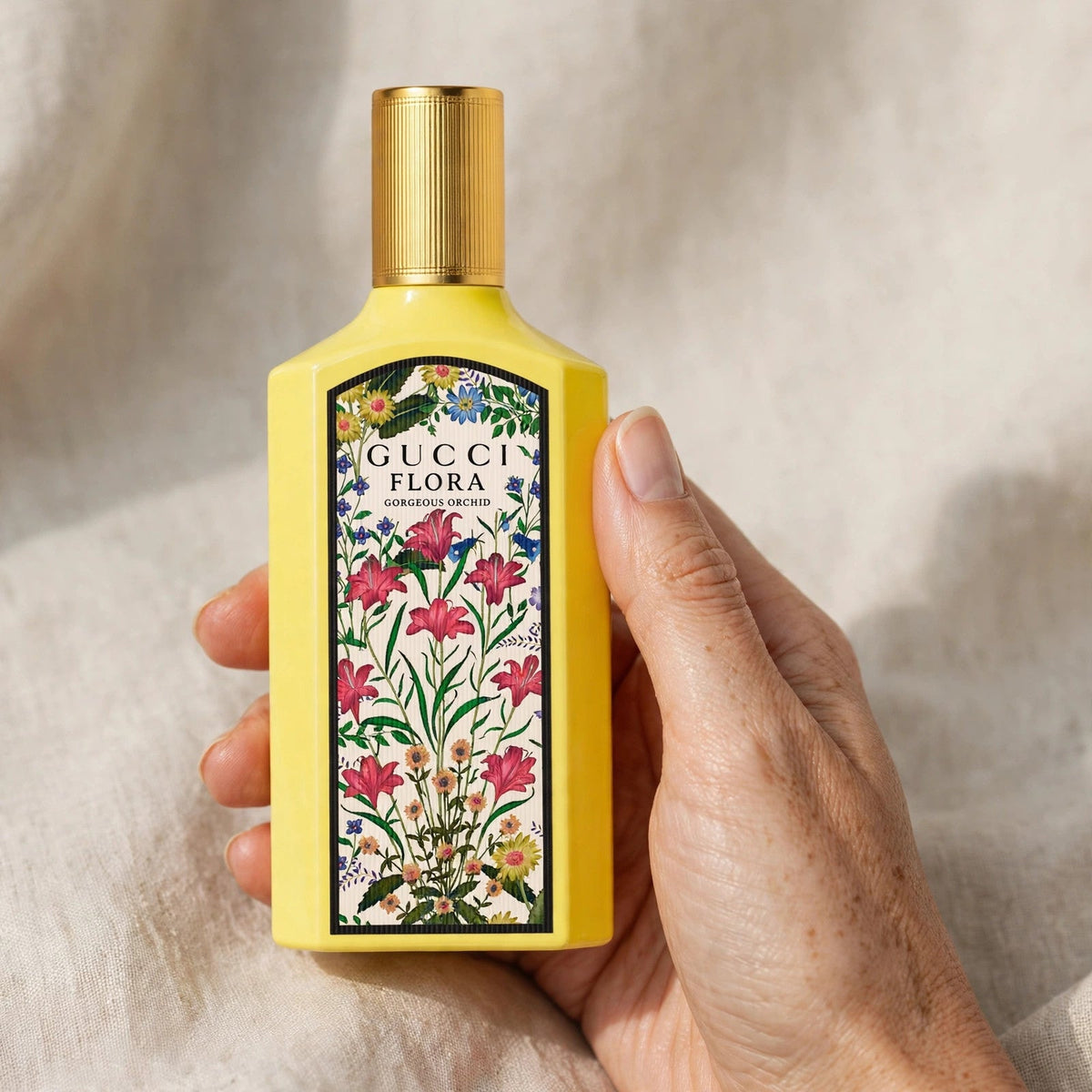 Hand holding Gucci Flora Gorgeous Orchid EDP perfume bottle