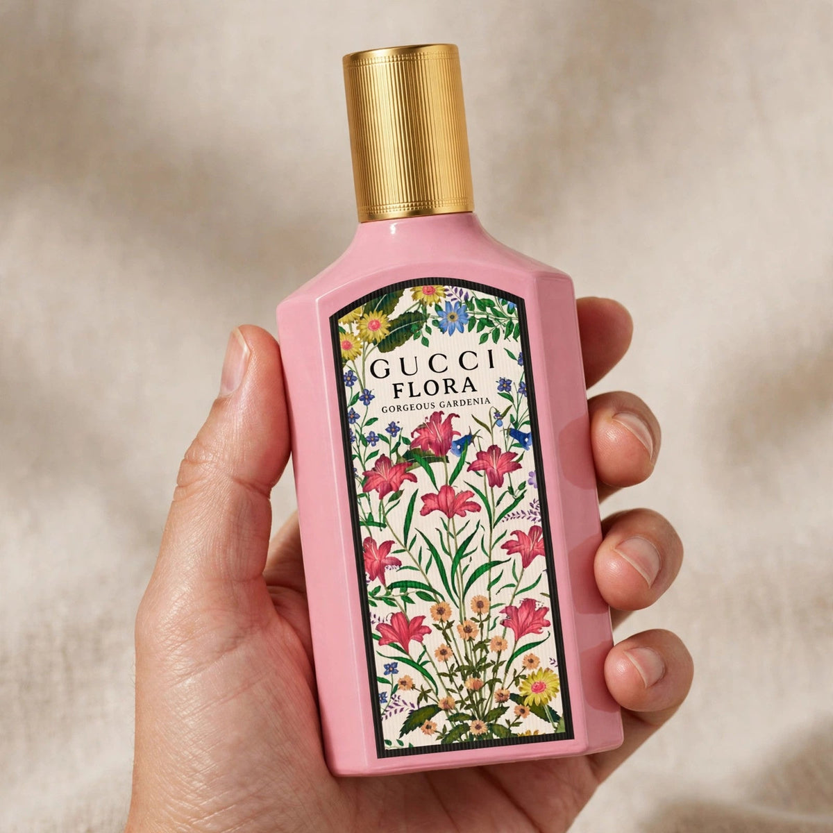 Hand holding Gucci Flora Gorgeous Gardenia EDP perfume bottle