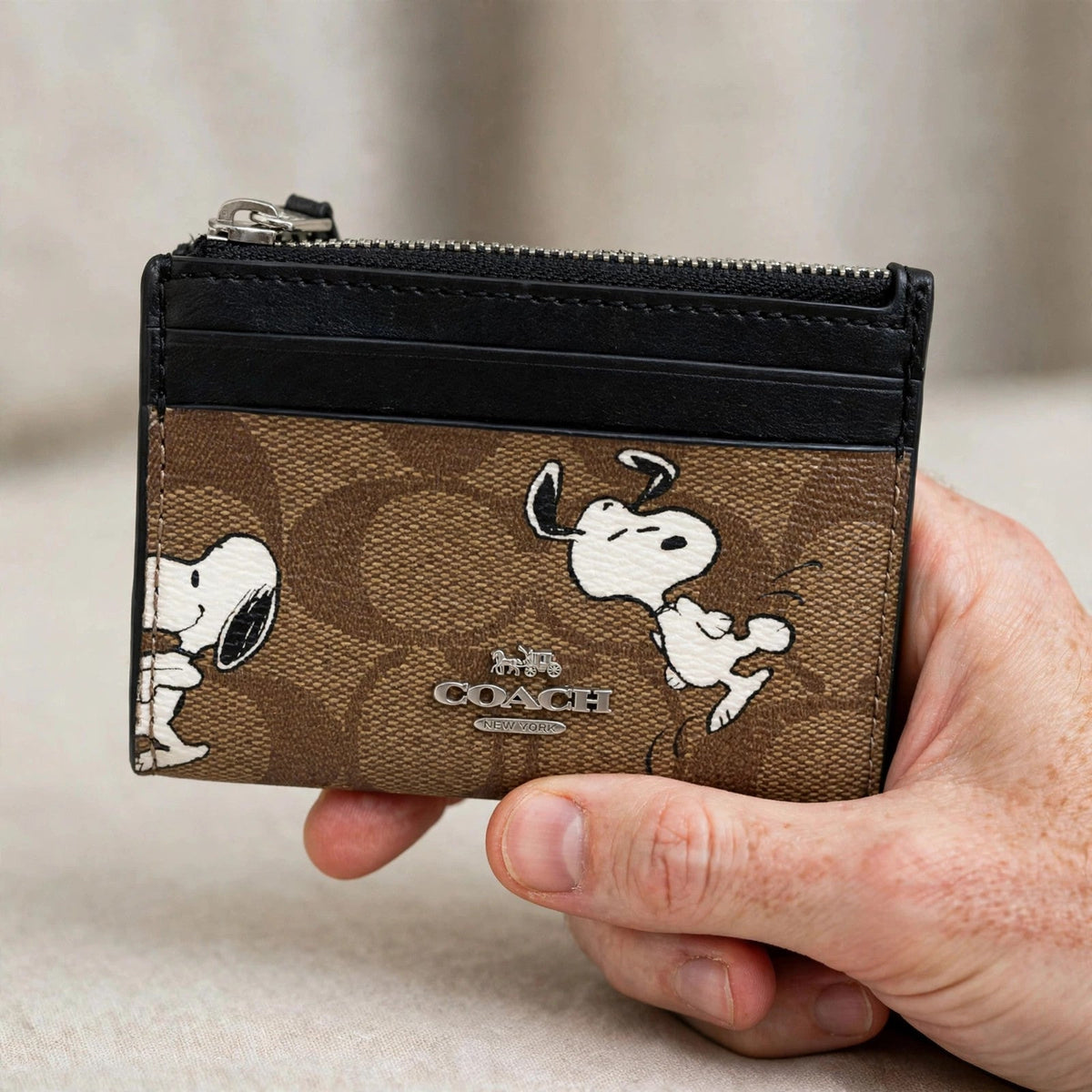Coach x Peanuts Mini Skinny ID Case – Signature Canvas Snoopy Print — hand product photo