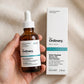 Hand holding The Ordinary Multi-Peptide hair serum bottle