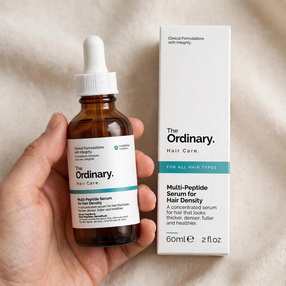 Hand holding The Ordinary Multi-Peptide hair serum bottle