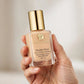 Hand holding Estee Lauder Double Wear foundation bottle