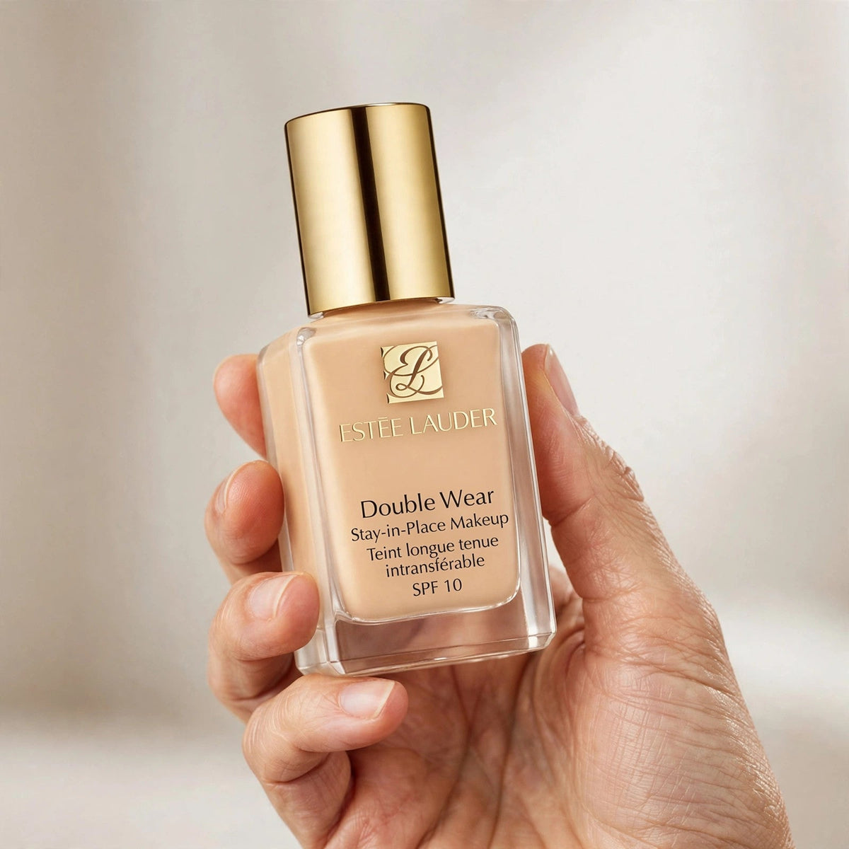 Hand holding Estee Lauder Double Wear foundation bottle