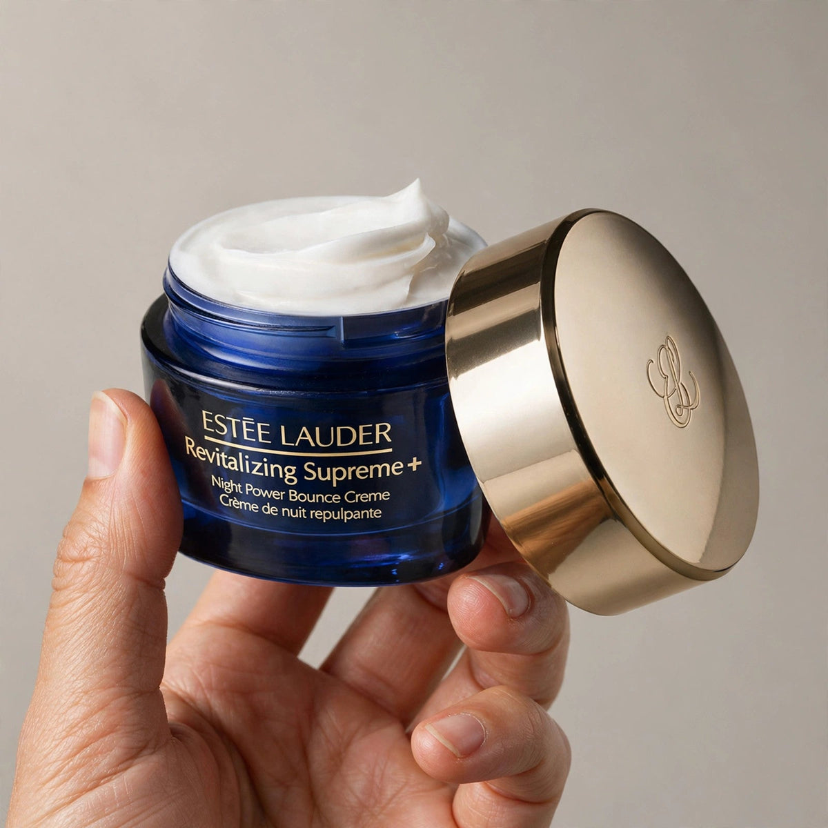 Hand holding Estee Lauder Night Power Bounce Creme jar