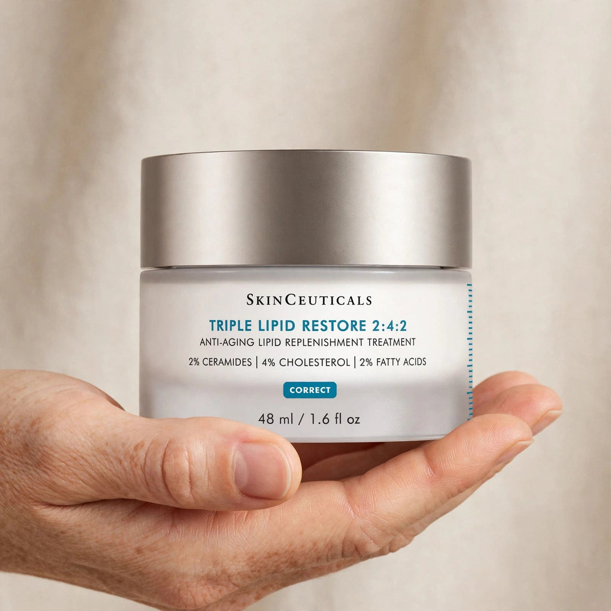 Hand holding SkinCeuticals Triple Lipid Restore jar