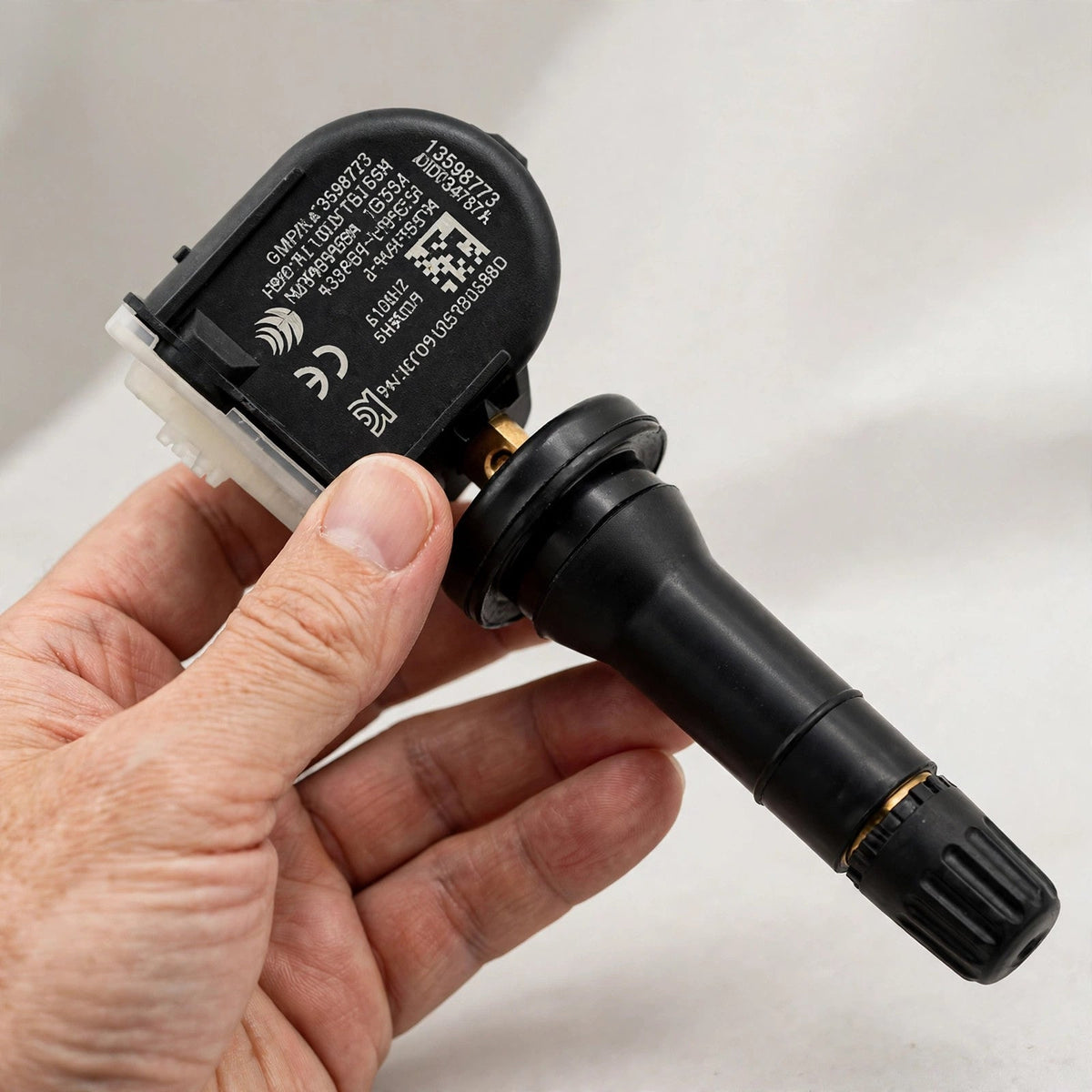 Hand holding a 13598773 TPMS tire pressure sensor